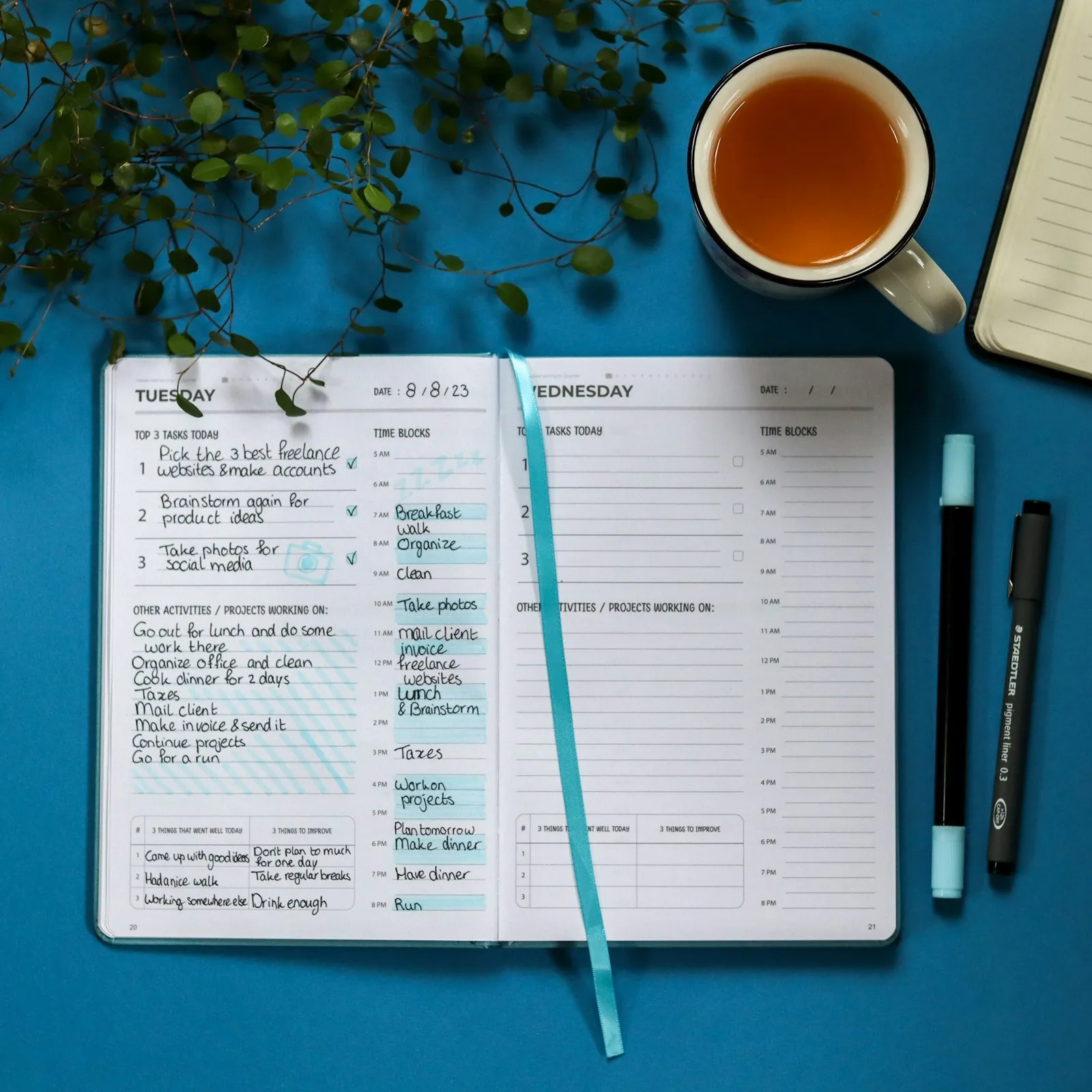 An open daily planner with handwritten notes next to a cup of tea