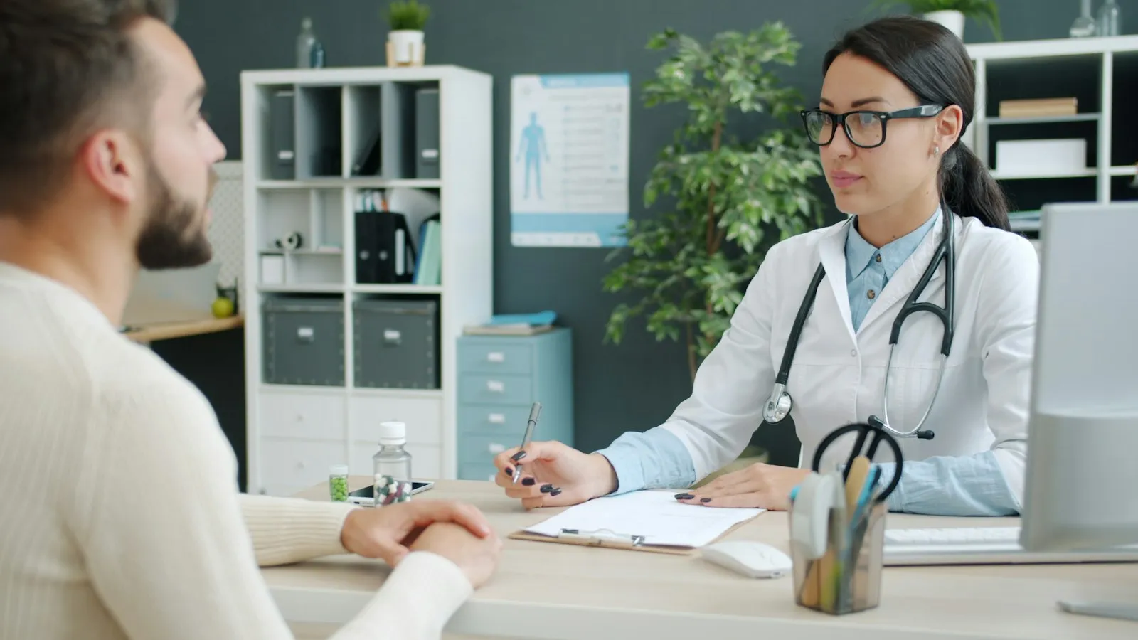 A doctor listening to a patient across a desk