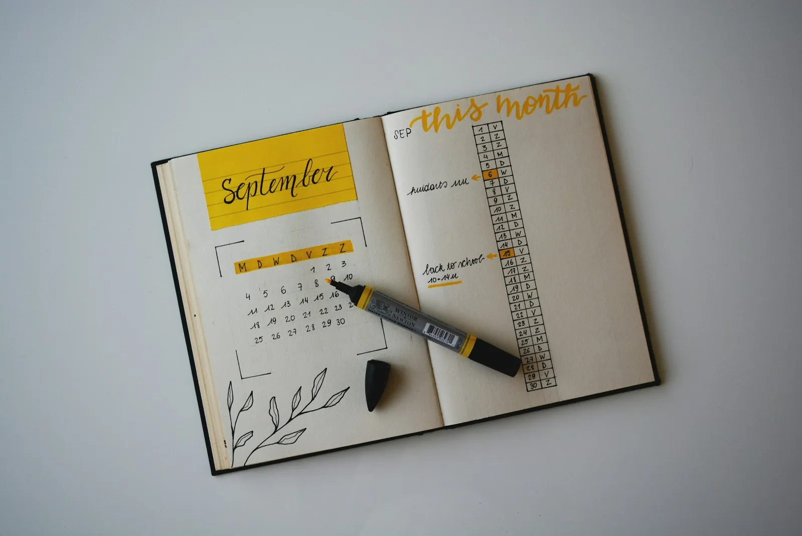 A monthly planner open on a desk with a marker pen